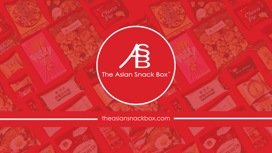 A variety of snacks in the background with The Asian Snack Box logo in a circle in the middle