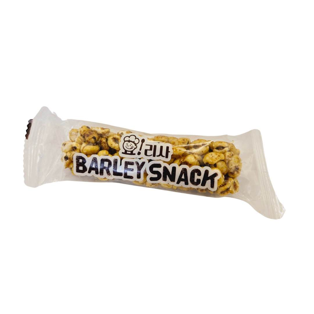 A transparent package of Yorisa round barley snack with visible roasted barley pieces inside. The label features a playful design with a cartoon character and the text "Barley Snack" in bold black letters.